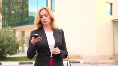 bir iş merkezi city, steadicam atış yürüme yürüyüş iş kadını bir smartphone ile iş takım elbiseli. 4k, ağır çekim, alanı Kopyala