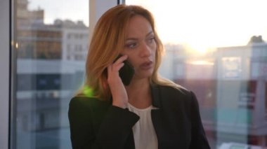 iş kadını bir iş takım elbise a smartphone ile panoramik pencerelere, 4 k, iş merkeziyle koridor boyunca yürüyüş yavaş hareket, kopyalamak için uzay