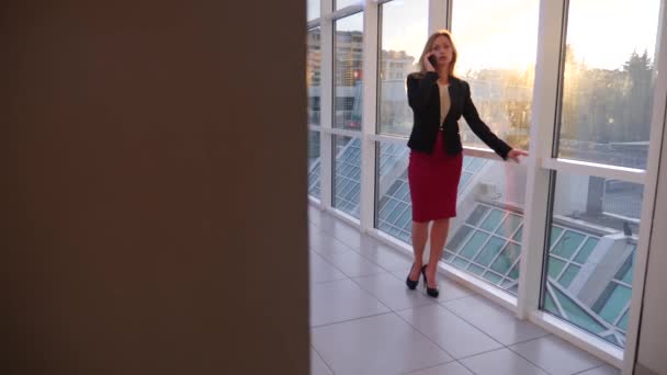 Business woman in a business suit with a smartphone, walking along the corridor of the business center with panoramic windows, 4k, slow motion, space for copying — Stock Video