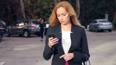 bir iş merkezi city, steadicam atış yürüme yürüyüş iş kadını bir smartphone ile iş takım elbiseli. 4k, ağır çekim, alanı Kopyala