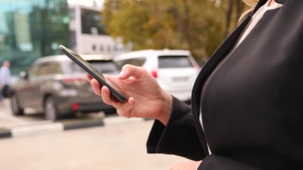Ділова жінка в діловому костюмі зі смартфоном, що йде по бізнес-центру, ходить по місту, стайка. 4k, повільний рух, простір копіювання — стокове відео