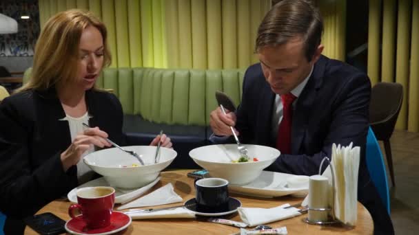 Parceiros de negócios homem e mulher almoçam em smartphones de uso de café. Espaço de cópia 4K — Vídeo de Stock