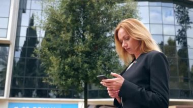 bir iş merkezi city, steadicam atış yürüme yürüyüş iş kadını bir smartphone ile iş takım elbiseli. 4k, ağır çekim, alanı Kopyala