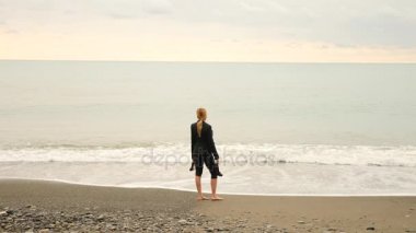 İşkadını takım ayakta sahilde. Deniz Manzaralı seviyor. 4k, ağır çekim.