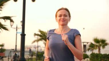 Road runner kadın palm grove çalışan kadın açık havada, koşu park, Park palmiye ağaçları, dolgu, yaz ile çalışan. 4 k yavaş hareket