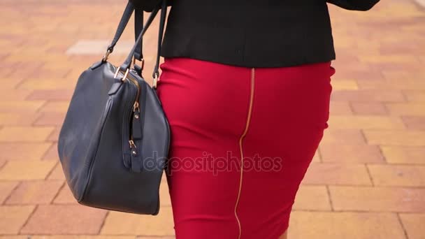 赤いスカートでセクシーな女性は、後ろからストリート、クローズ アップ ビューを歩いています。4 k、スローモーション — ストック動画