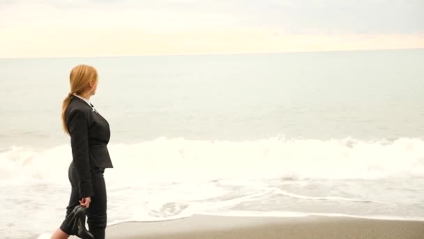 Mujer de negocios en traje de pie en la playa. disfruta de la vista al mar. 4k, cámara lenta . — Vídeo de stock