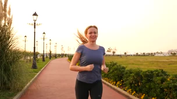 Road runner vrouw uitgevoerd in park, joggen langs de palmentuin, Running vrouw buitenshuis, Park met palmbomen, embankment, zomer. 4 k slow-motion — Stockvideo