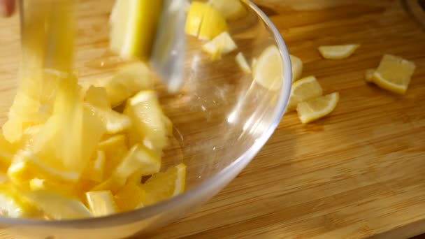Iemand een citroen op de snijplank te snijden in kleine stukjes. 4 k, vertraagd, close-up — Stockvideo