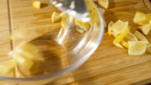Alguém cortou um limão na tábua de cortar em pequenos pedaços. 4k, câmera lenta, close-up — Vídeo de Stock