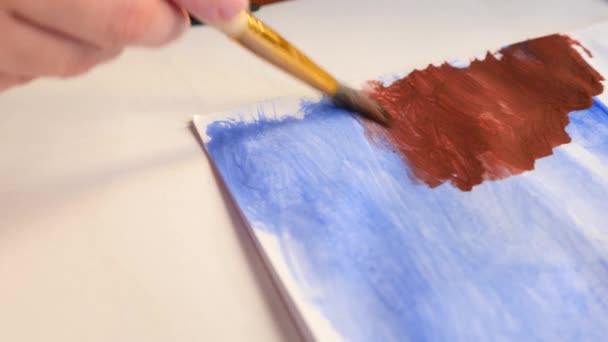 Ο καλλιτέχνης χρωματίζει τα χρώματα σε ένα λευκό φύλλο. κοντινό πλάνο του μια φούντα. 4k, αργή κίνηση γυρίσματα — Αρχείο Βίντεο