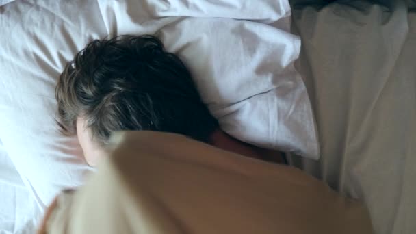 Человек с лихорадкой лежит дома в постели. 4k, slow motion — стоковое видео