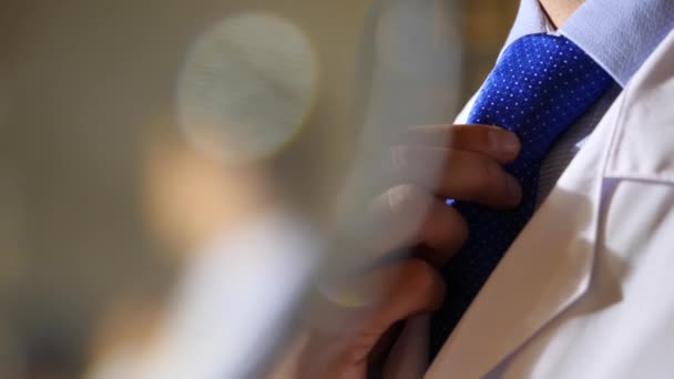 Человек в деловом костюме и галстуке надевает белый халат. 4k, slow motion — стоковое видео