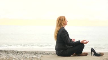 İşkadını plaj elbiseli. lotus pozisyonda oturan ve deniz kenarında meditasyon. 4k, ağır çekim