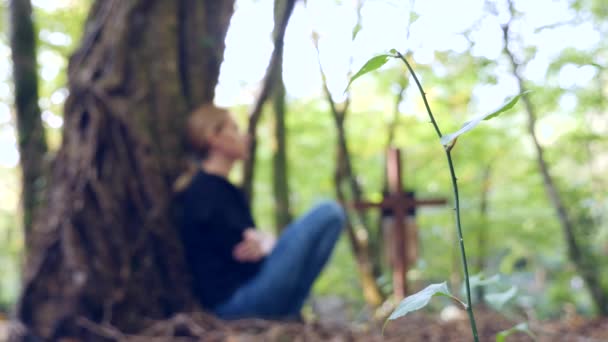 Une femme en chemisier noir dans un cimetière à côté de la tombe. 4k, au ralenti. espace de copie — Video