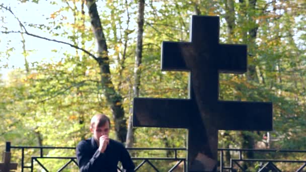 Человек в черной рубашке на кладбище рядом с могилой. 4К, замедленная съемка. место для копирования — стоковое видео