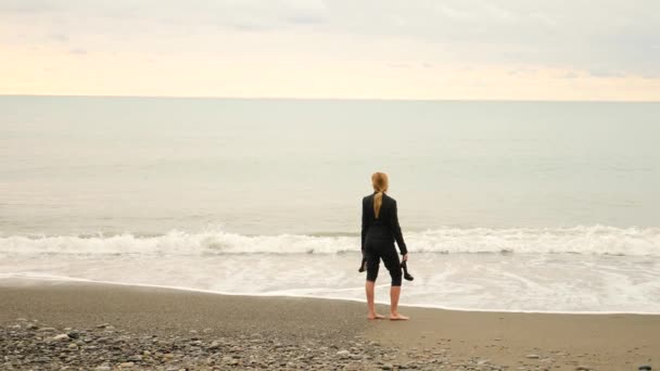 Businesswoman in suit standing on beach. she enjoys the sea view. 4k, slow motion. feet in waves close up — Stock Video