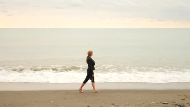 女商人在西装站在海滩上。她喜欢的海景。4 k，慢动作。脚在波浪中的关闭 — 图库视频影像