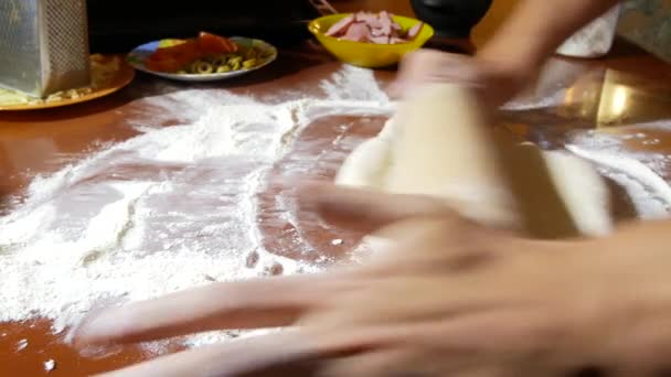 男は、料理のピザ、生地を練り、家族は台所で料理をします。4 k. クローズ アップ — ストック動画