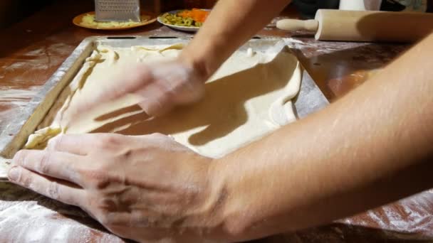 L'uomo impasta l'impasto, cucina la pizza, la famiglia cucina in cucina. 4k. primo piano — Video Stock