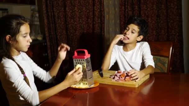 Hermano y hermana cortaron un relleno para pizza. cocinar pizza, la familia está cocinando en la cocina. 4k — Vídeo de stock