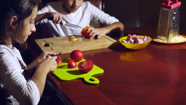 Bror och syster skär en fyllning för pizza. matlagning pizza, familjen är matlagning i köket. 4k — Stockvideo