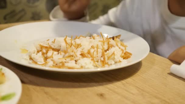 El niño está comiendo arroz al curry con chuleta de cerdo. 4k — Vídeo de stock