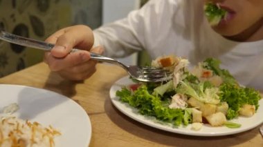 Bir oğlan Sezar salata çatalı tarafından yiyor. 4k