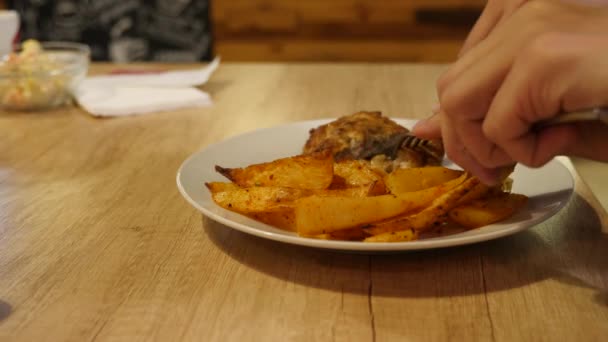 O homem está comendo costeletas de carne frita com batata assada em especiarias. 4k . — Vídeo de Stock