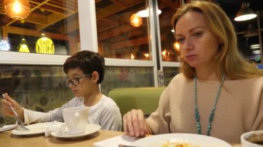 Restoranda oturan oğlu ile annesi. bir iştahla yemek. 4k