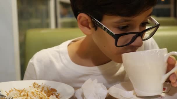 O rapaz está a beber chá num café. 4k — Vídeo de Stock