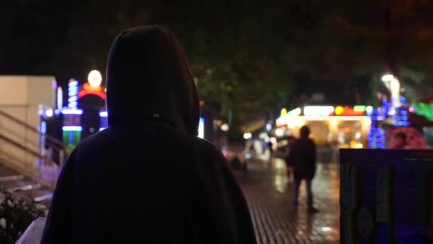 Silhueta de um homem de capuz numa rua nocturna. 4k — Vídeo de Stock