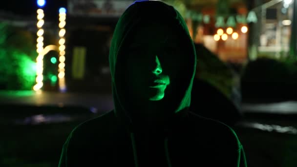 Силуэт человека в капюшоне, стоящего на ночной улице. 4k — стоковое видео