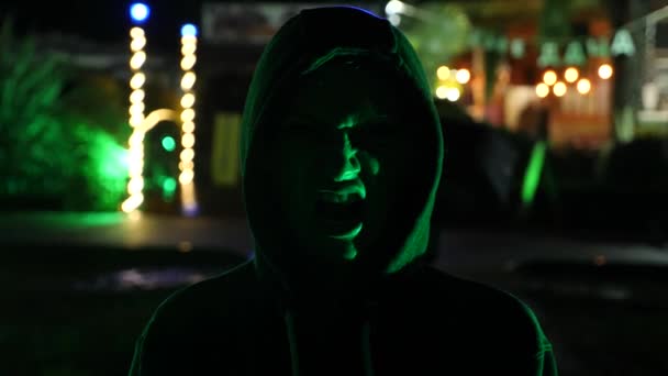 Silhouette d'un homme dans un capot debout dans une rue nocturne. 4k — Video