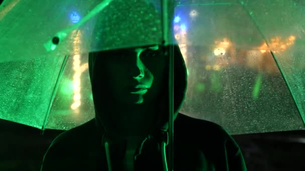 Silhouette d'un homme dans un capot debout dans une rue nocturne. 4k — Video