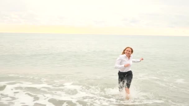 Podnikatel v obleku na pláži. Ona běží od vlny. 4k, pomalý pohyb — Stock video