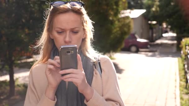 Mujer joven usando un teléfono inteligente, de pie en una zona comercial de la ciudad, 4k. Movimiento lento — Vídeo de stock