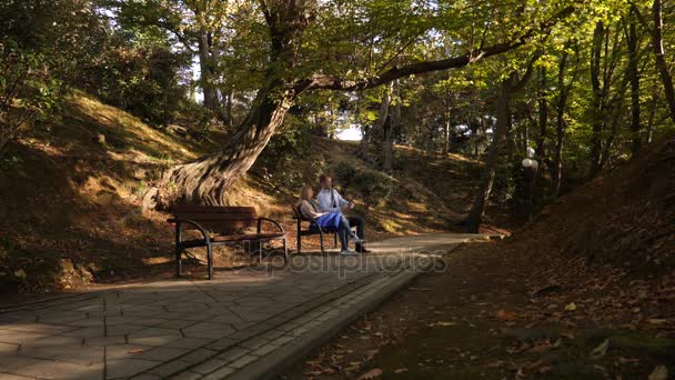 4k, slow motion, the girl and the guy with the camera are sitting on a bench in a picturesque place. — Stock Video