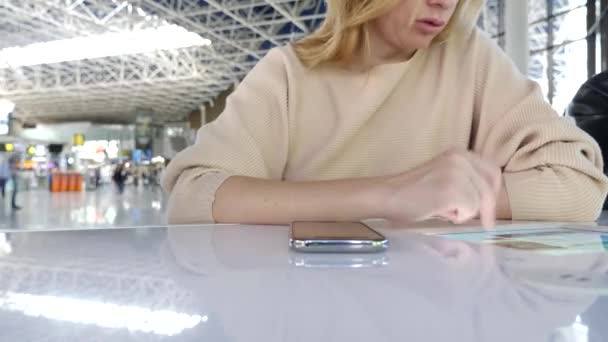 Kadın bir smartphone Havaalanı lounge bekleyen kullanır. Havaalanında uçuş beklentilerini. 4k, ağır çekim — Stok video