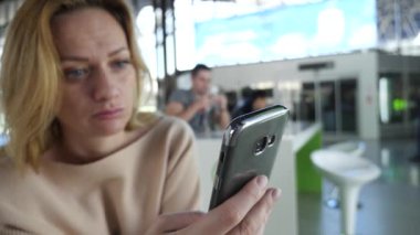 Kadın bir smartphone Havaalanı lounge bekleyen kullanır. Havaalanında uçuş beklentilerini. 4k, ağır çekim