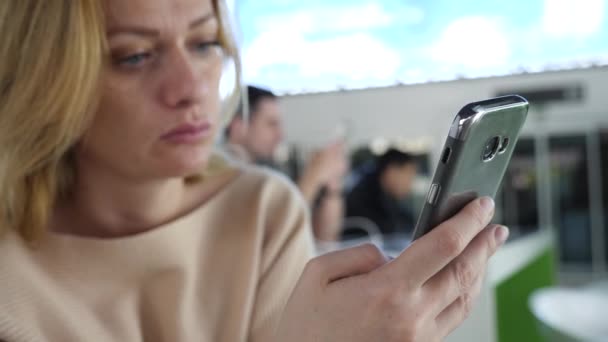 Mujer utiliza un teléfono inteligente en la sala de espera del aeropuerto. Expectativas de vuelo en el aeropuerto. 4k, cámara lenta — Vídeo de stock