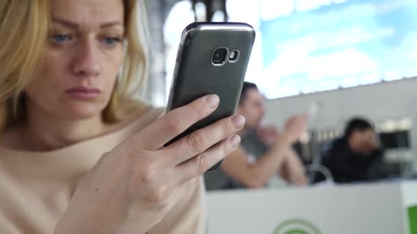 Kvinnan använder en smartphone i flygplats väntar lounge. Förväntningar på flyg på flygplatsen. 4k, Slowmotion — Stockvideo