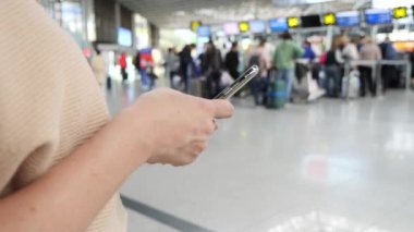 Kadın bir smartphone Havaalanı lounge bekleyen kullanır. Havaalanında uçuş beklentilerini. 4k, ağır çekim