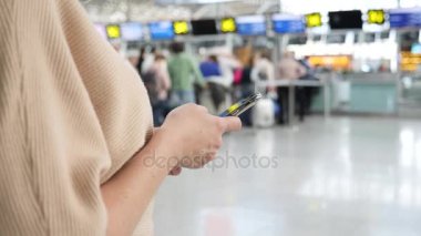 Kadın bir smartphone Havaalanı lounge bekleyen kullanır. Havaalanında uçuş beklentilerini. 4k, ağır çekim
