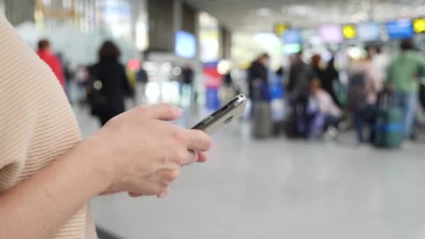 Mujer utiliza un teléfono inteligente en la sala de espera del aeropuerto. Expectativas de vuelo en el aeropuerto. 4k, cámara lenta — Vídeo de stock