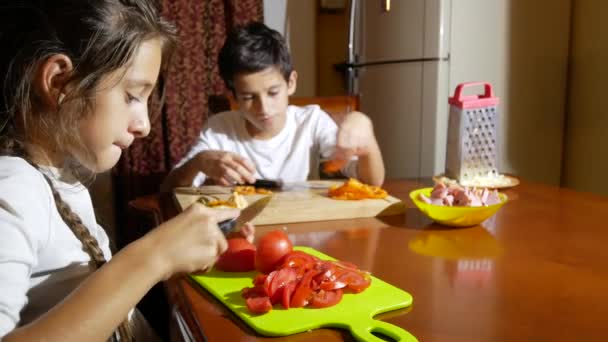 Bruder und Schwester schneiden eine Füllung für Pizza. Während die Familie Pizza kocht, kocht sie in der Küche. 4k — Stockvideo