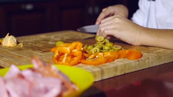 Nahaufnahme. Bruder und Schwester schneiden eine Füllung für Pizza. Während die Familie Pizza kocht, kocht sie in der Küche. 4k — Stockvideo