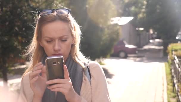 Mujer joven usando un teléfono inteligente, de pie en una zona comercial de la ciudad, 4k. Movimiento lento — Vídeos de Stock