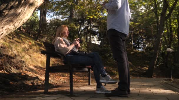 4k, au ralenti, fille avec une caméra est assis sur un banc dans un endroit pittoresque. Les passants passent devant . — Video