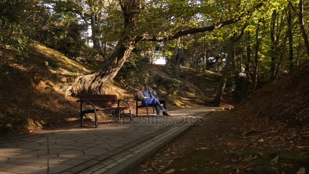 4k, Slowmotion, het meisje en de man met de camera zitten op een bankje in een pittoreske plaats. — Stockvideo